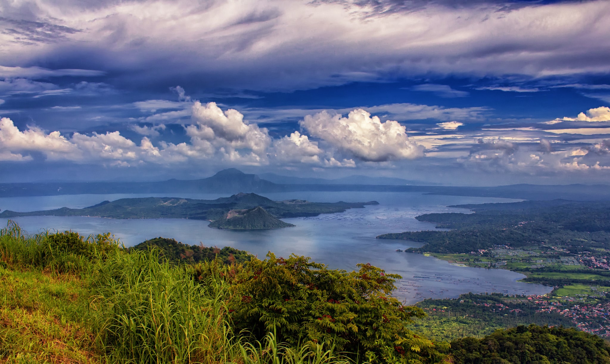 Landscape photo of a volcano in the ocean with some greenery in the forefront