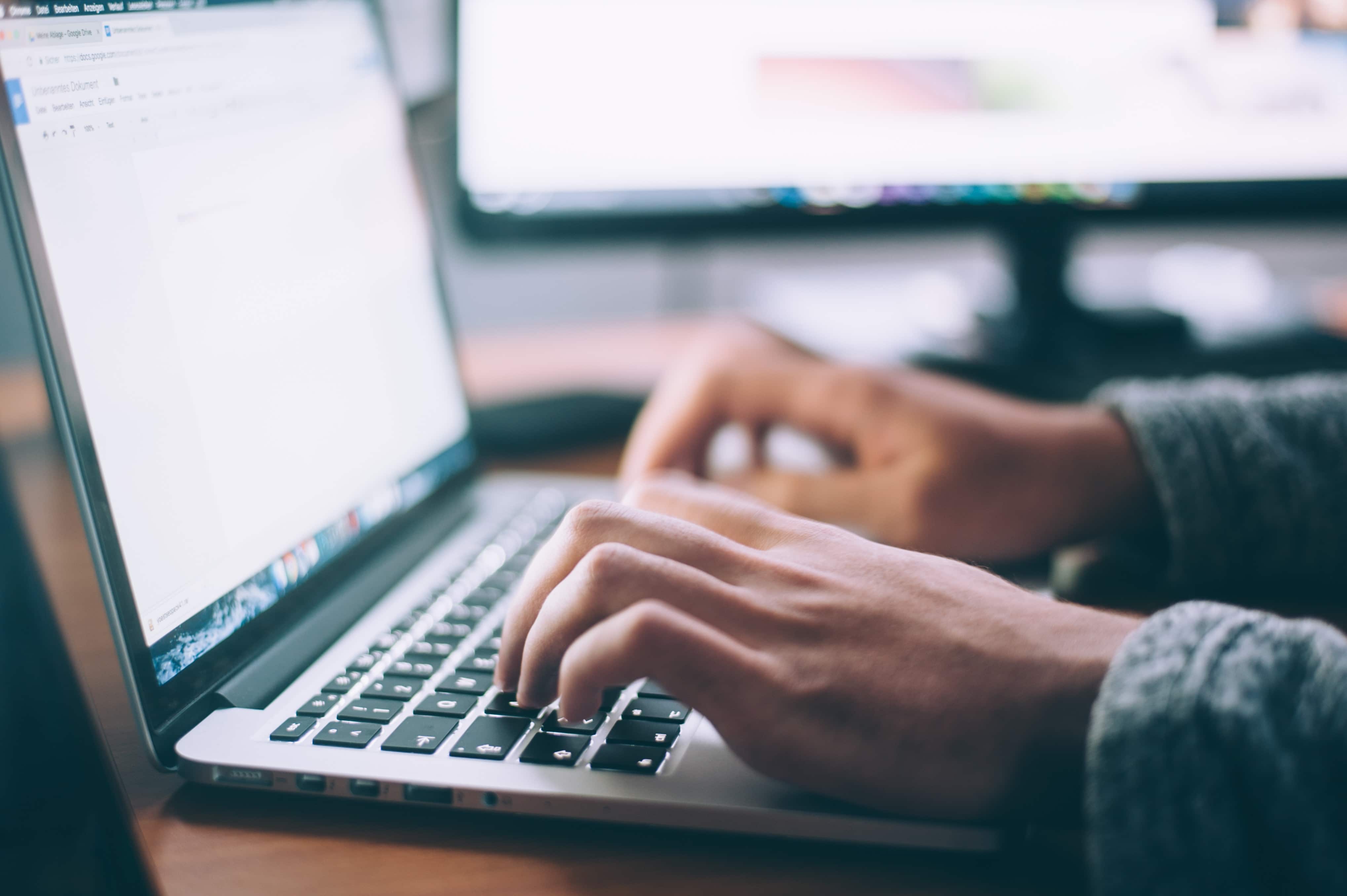 Person's hands typing on a laptop computer